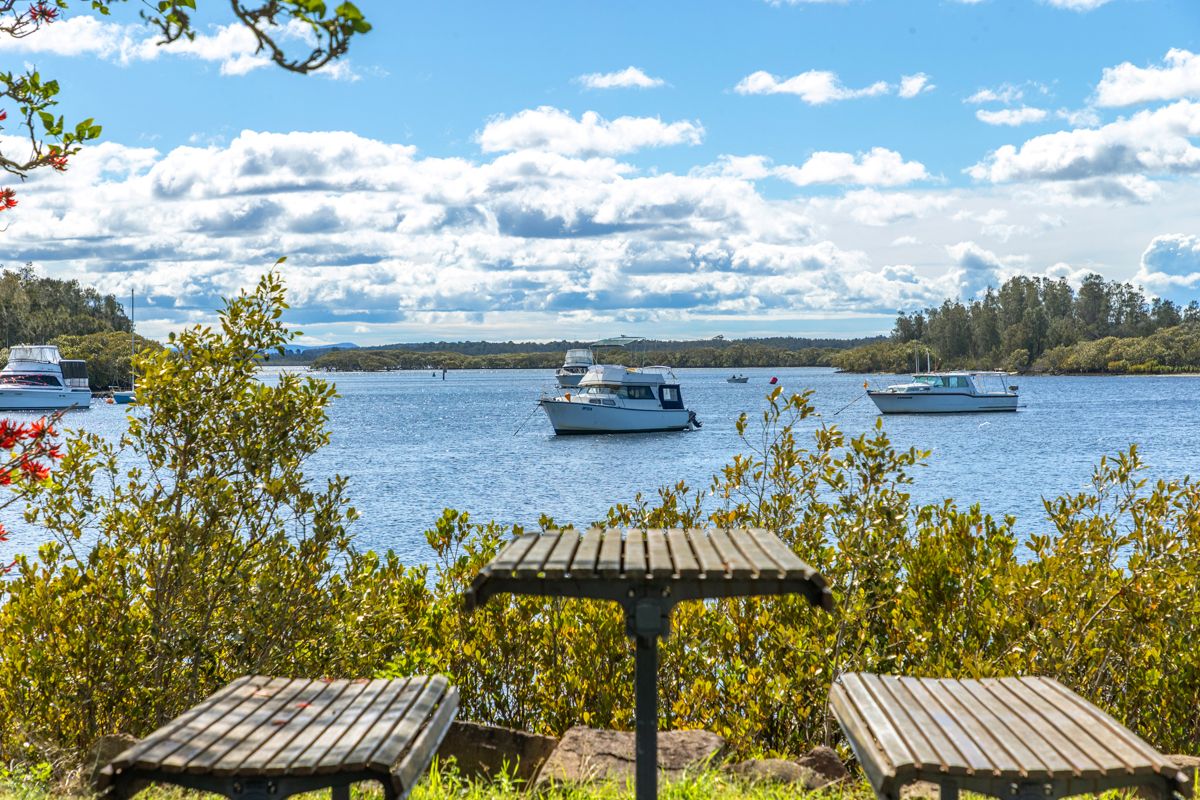 Picnic tables on the Myall River foreshore with cruisers moored offshore